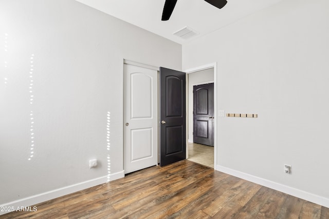 unfurnished bedroom with a ceiling fan, wood finished floors, visible vents, and baseboards