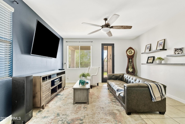 living room with light tile patterned floors, a ceiling fan, and baseboards