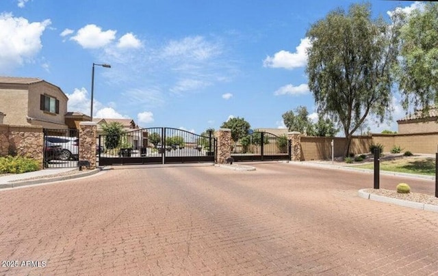 view of street featuring curbs, a gated entry, sidewalks, and a gate