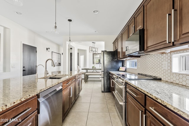 kitchen featuring a sink, tasteful backsplash, stainless steel appliances, light tile patterned floors, and light stone countertops