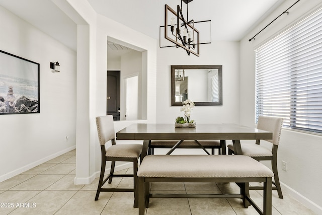 dining area featuring an inviting chandelier, light tile patterned floors, and baseboards