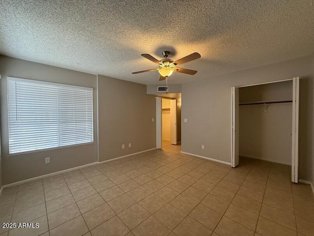 unfurnished bedroom with light tile patterned floors, a textured ceiling, a closet, and ceiling fan