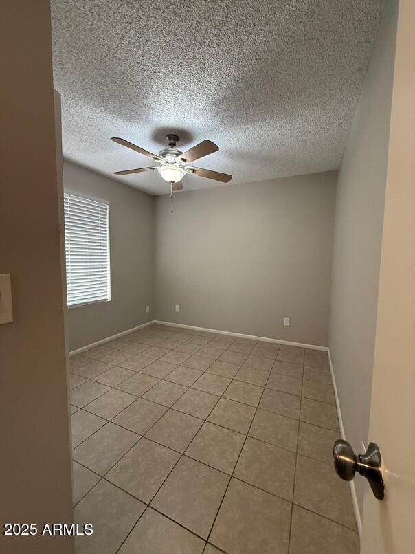 spare room featuring light tile patterned flooring, a textured ceiling, and ceiling fan