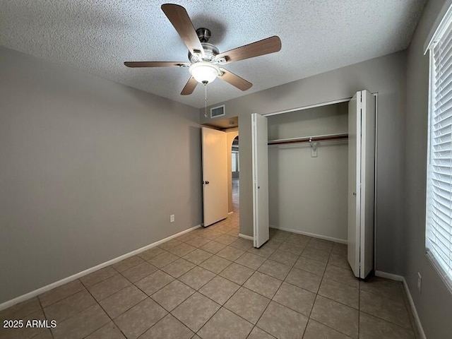 unfurnished bedroom with light tile patterned floors, a textured ceiling, a closet, and ceiling fan