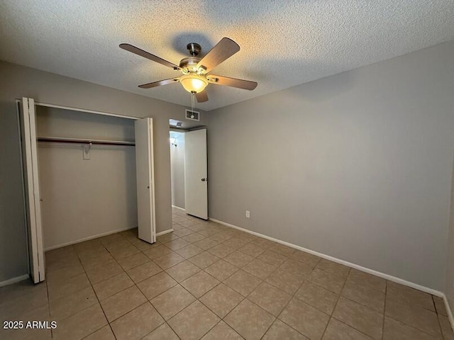 unfurnished bedroom featuring ceiling fan, light tile patterned floors, a closet, and a textured ceiling