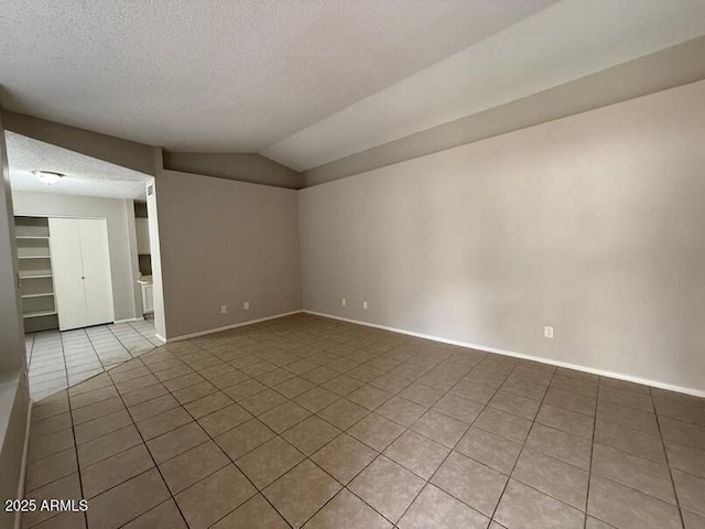 tiled empty room with lofted ceiling and a textured ceiling