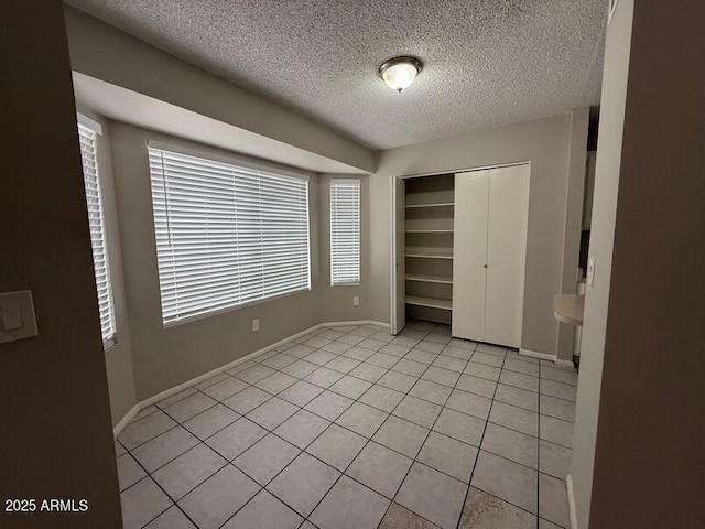 unfurnished bedroom featuring a closet, a textured ceiling, and light tile patterned flooring