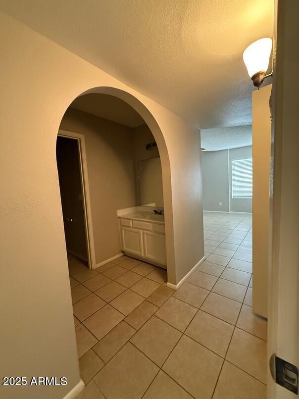 hallway featuring sink, light tile patterned floors, and a textured ceiling