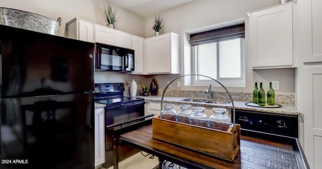 kitchen with light stone counters, sink, black appliances, wood-type flooring, and white cabinetry