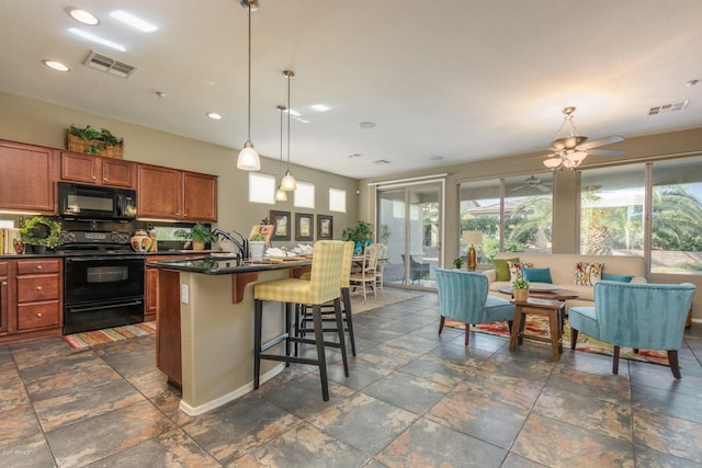 kitchen with black appliances, hanging light fixtures, ceiling fan, a breakfast bar area, and a kitchen island with sink