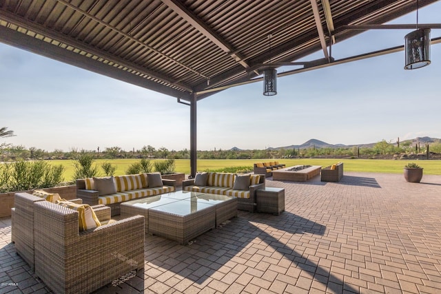 view of patio featuring a mountain view, an outdoor living space with a fire pit, and a rural view