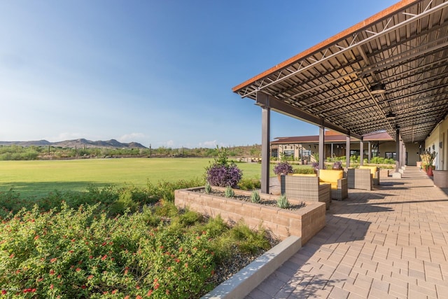 view of property's community featuring a patio area, a lawn, and a mountain view