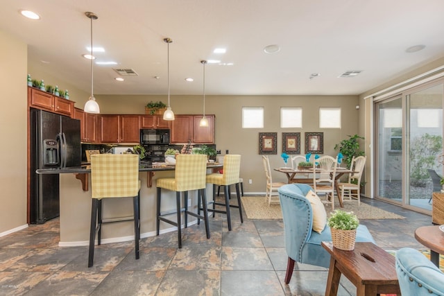 kitchen featuring tasteful backsplash, black appliances, decorative light fixtures, and a kitchen bar