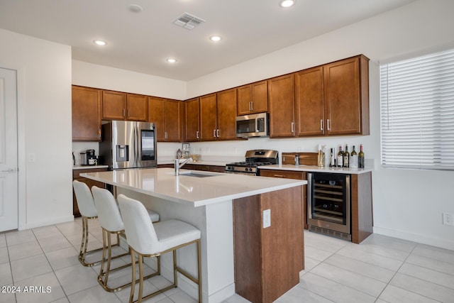 kitchen with sink, beverage cooler, stainless steel appliances, a kitchen island with sink, and light tile patterned floors