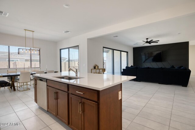 kitchen with sink, hanging light fixtures, stainless steel dishwasher, ceiling fan, and an island with sink