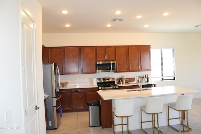 kitchen featuring a kitchen island with sink, sink, light tile patterned floors, and stainless steel appliances