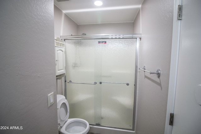 bathroom featuring a shower with shower door and toilet