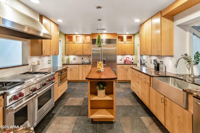 kitchen with a wealth of natural light, sink, wooden counters, range hood, and high end appliances