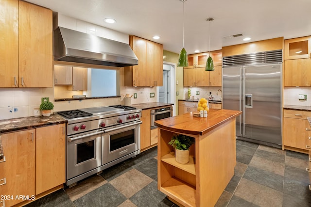 kitchen featuring wood counters, backsplash, high end appliances, exhaust hood, and decorative light fixtures