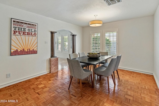 dining room featuring decorative columns, a textured ceiling, and parquet flooring