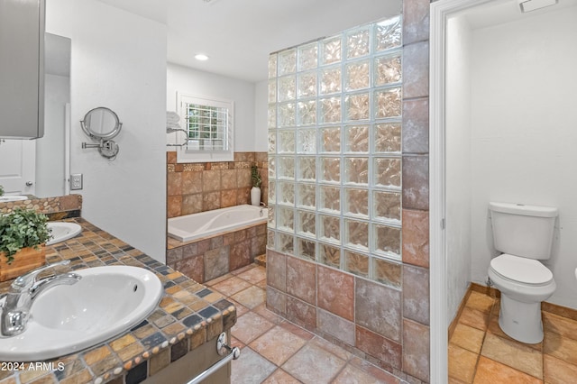 bathroom with tiled bath, vanity, and toilet