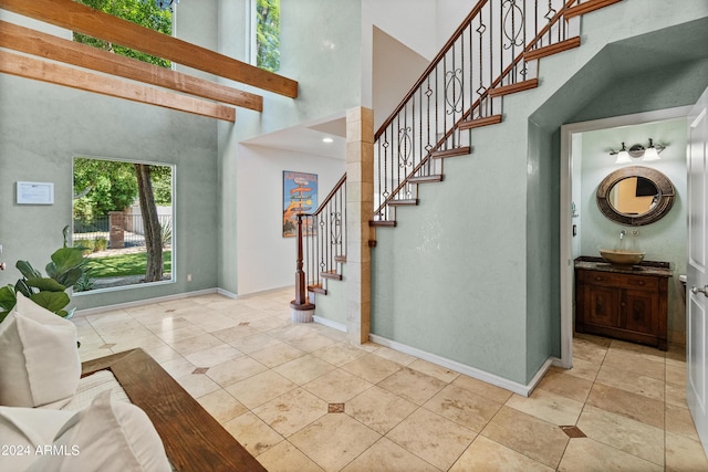 foyer with light tile patterned floors, a towering ceiling, and sink