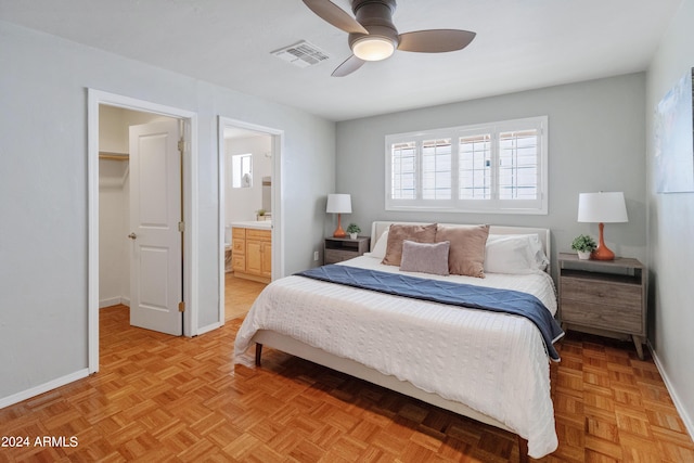 bedroom with ensuite bath, ceiling fan, light parquet floors, and a spacious closet