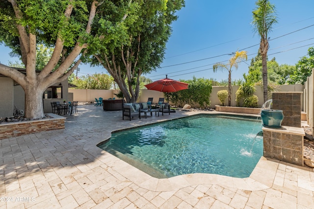 view of pool featuring pool water feature, a patio, and an outdoor living space