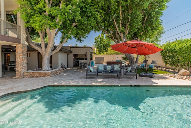 view of swimming pool featuring an outdoor kitchen, outdoor lounge area, a patio, and grilling area