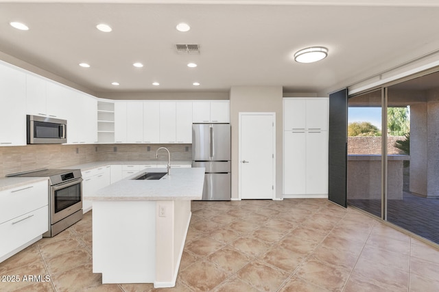 kitchen featuring decorative backsplash, stainless steel appliances, a kitchen island with sink, sink, and white cabinets