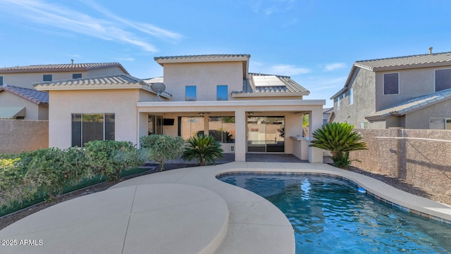 back of property featuring a fenced in pool and a patio