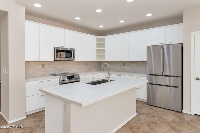 kitchen featuring white cabinets, stainless steel appliances, a kitchen island with sink, and sink