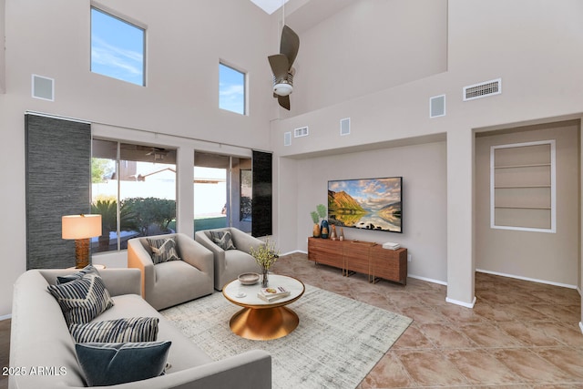 living room featuring built in shelves, ceiling fan, and a high ceiling