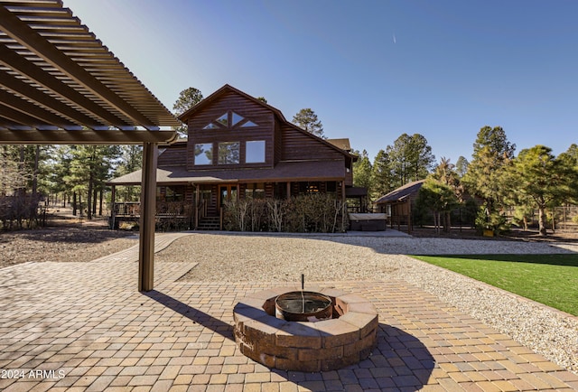 back of house featuring a fire pit, a pergola, a patio, and a hot tub