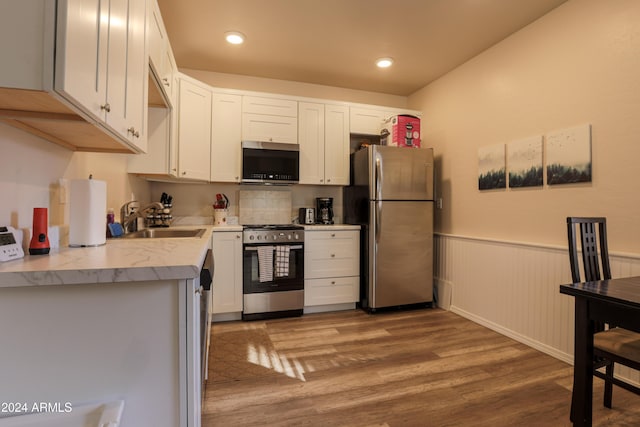 kitchen featuring white cabinets, appliances with stainless steel finishes, light hardwood / wood-style floors, and sink