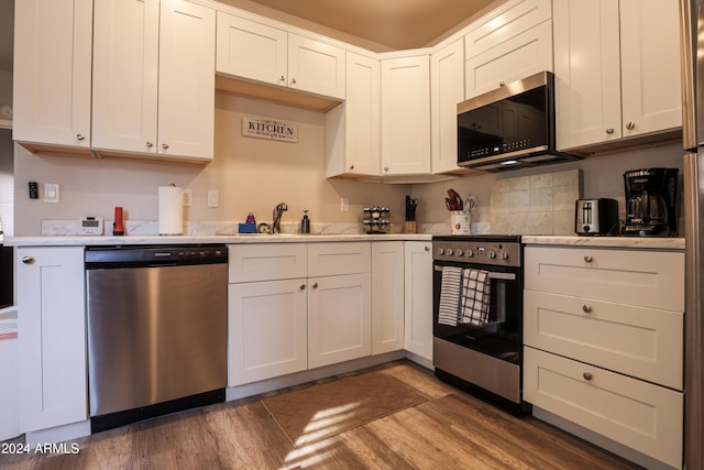 kitchen with white cabinets, appliances with stainless steel finishes, dark wood-type flooring, and sink