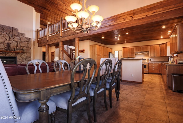 tiled dining area featuring sink, an inviting chandelier, a stone fireplace, and wood ceiling