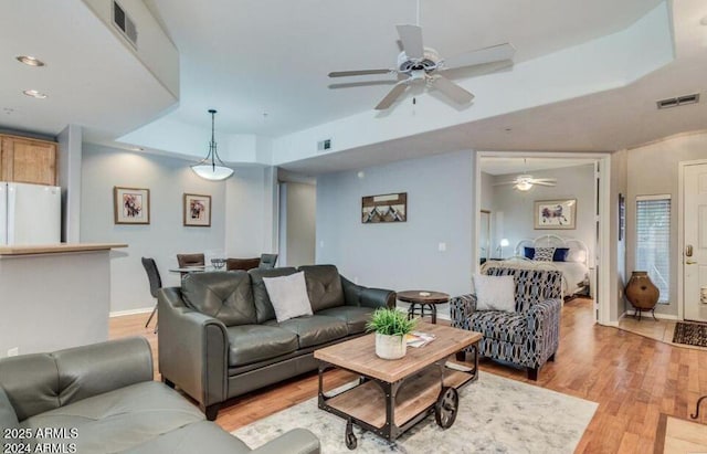 8245 E Bell Rd Unit 103, Scottsdale, AZ 85260 - living room with light wood finished floors, a ceiling fan, baseboards, recessed lighting, and a tray ceiling