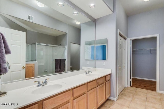 8245 E Bell Rd Unit 103, Scottsdale, AZ 85260 - bathroom featuring a shower stall, tile patterned floors, double vanity, baseboards, and a spacious closet