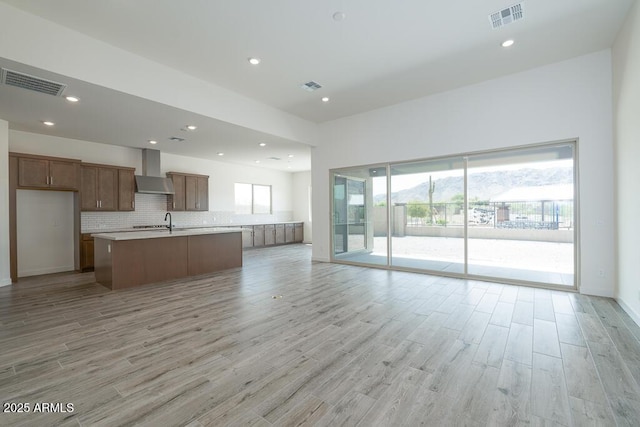 9775 S 36th Ln, Laveen, AZ 85339 - kitchen featuring open floor plan, wall chimney exhaust hood, a sink, light wood-style floors, and light countertops
