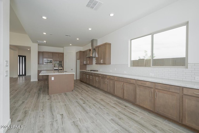 9775 S 36th Ln, Laveen, AZ 85339 - kitchen with wall chimney exhaust hood, stainless steel appliances, a sink, backsplash, and light wood-type flooring