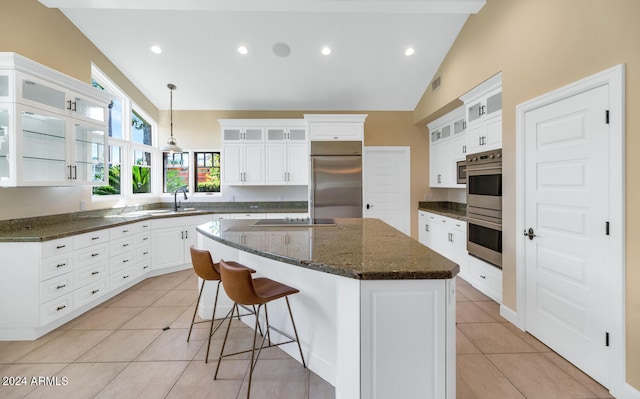 kitchen featuring pendant lighting, lofted ceiling, a kitchen island, white cabinetry, and stainless steel appliances