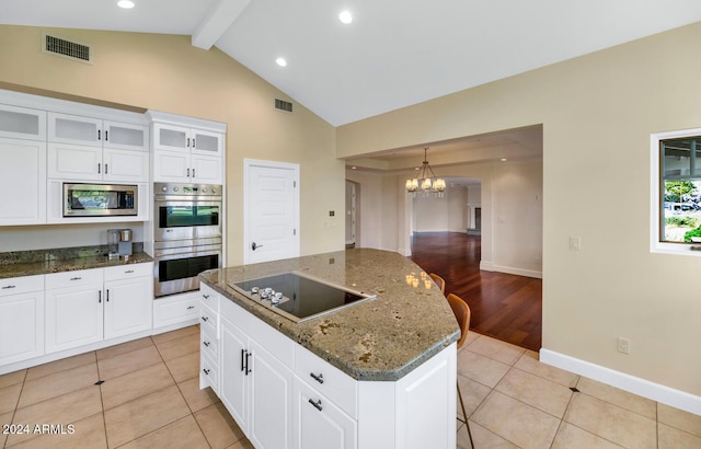 kitchen with appliances with stainless steel finishes, dark stone counters, white cabinets, light hardwood / wood-style floors, and a kitchen island