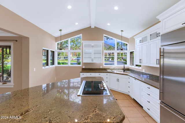 kitchen featuring black electric cooktop, built in refrigerator, dark stone counters, and decorative light fixtures