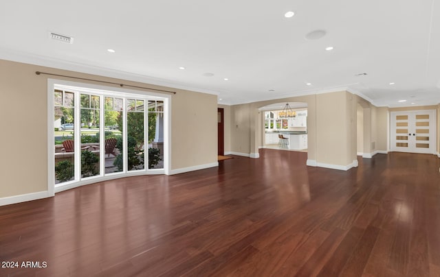 unfurnished living room with dark hardwood / wood-style floors, ornamental molding, and a notable chandelier