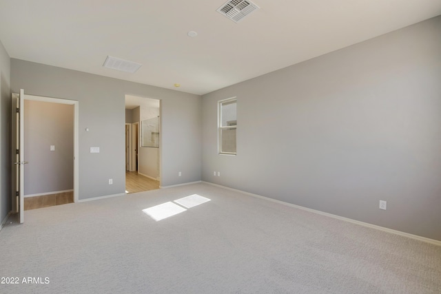 unfurnished bedroom with connected bathroom and light colored carpet