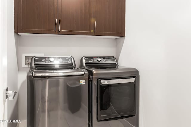 clothes washing area featuring cabinet space and washer and clothes dryer