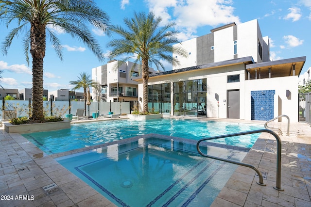 view of swimming pool with a pool with connected hot tub, fence, and a patio