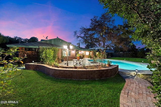 pool at dusk featuring a yard and a patio area