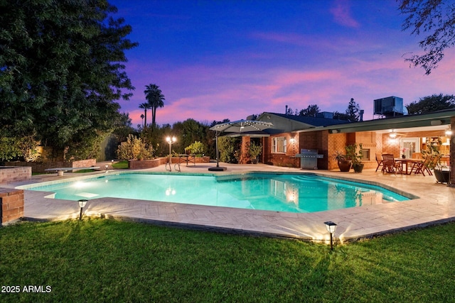 pool at dusk with area for grilling, central AC, a yard, and a patio area